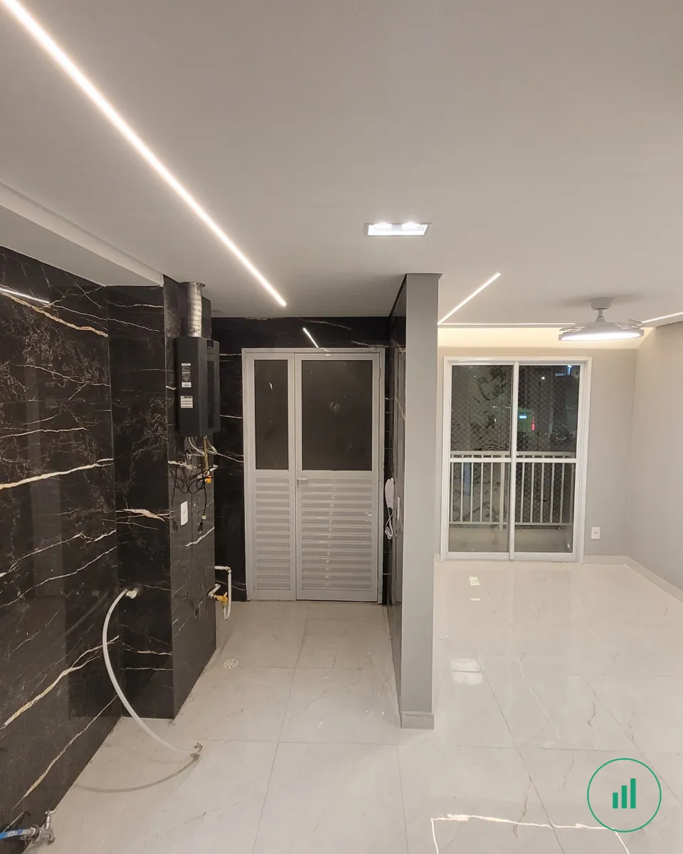 Apartamento reformado — cozinha com parede de porcelanato marmorizado e iluminação em LED